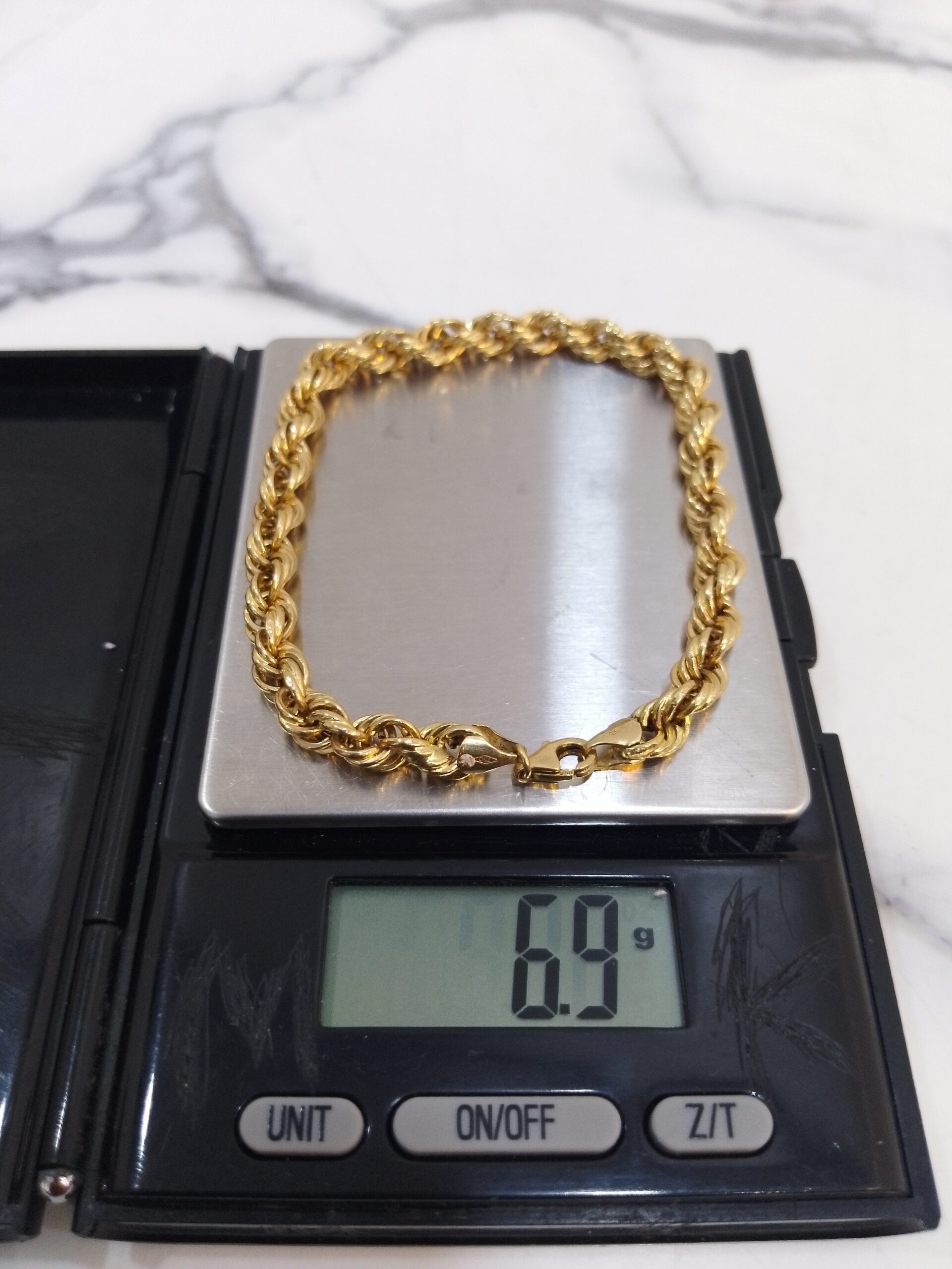 6.9g 18K yellow gold twisted chain bracelet 8 inches on a scale